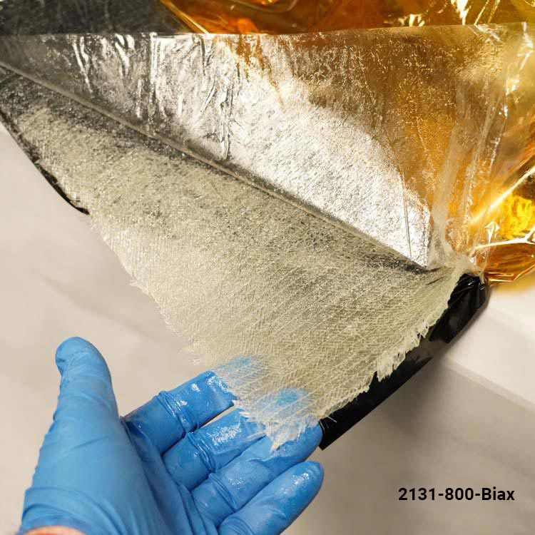 Person wearing blue gloves holding a roll of reflective insulation with a brand name.